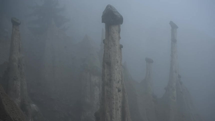 Eerie earth pyramids known as the Pyramids of Euseigne are shrouded in thick, rolling fog