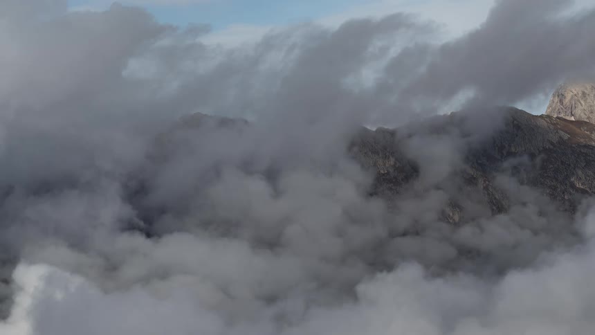 A serene view from above as clouds slowly drift over a rocky mountain range
