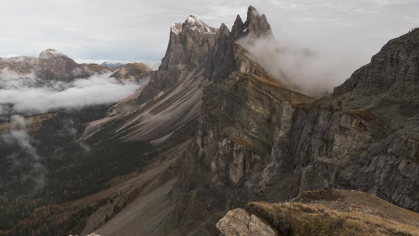 A dramatic timelapse reveals the majestic, jagged peaks of the Seceda ridgeline as clouds and fog dissipate from the mountain valley