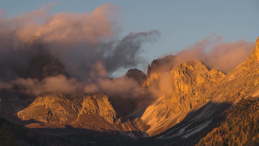 A beautiful time-lapse of clouds clearing over the Dolomites as the sun sets, casting a stunning alpenglow on the rugged peaks