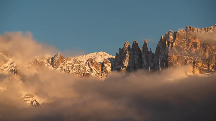 Clouds clear in a time-lapse revealing stunning, snow-capped mountain peaks at sunrise