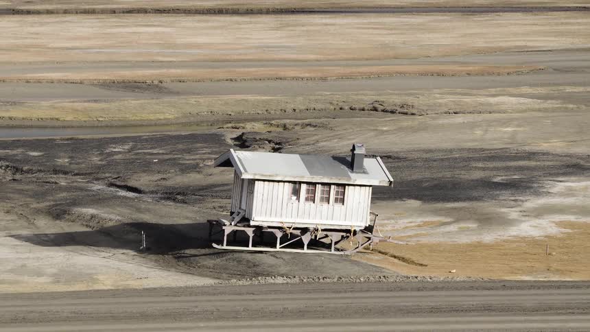 A remote cabin on skids slowly tilts and sinks into the ground as the arctic permafrost thaws due to climate change