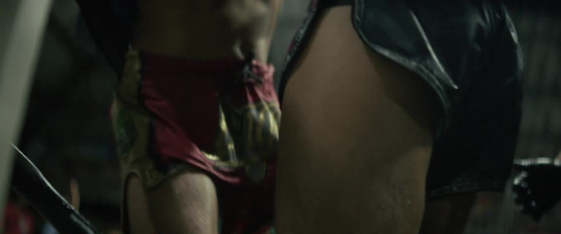 A gritty slow-motion close-up captures two Muay Thai fighters grappling and delivering powerful knee strikes in the ring