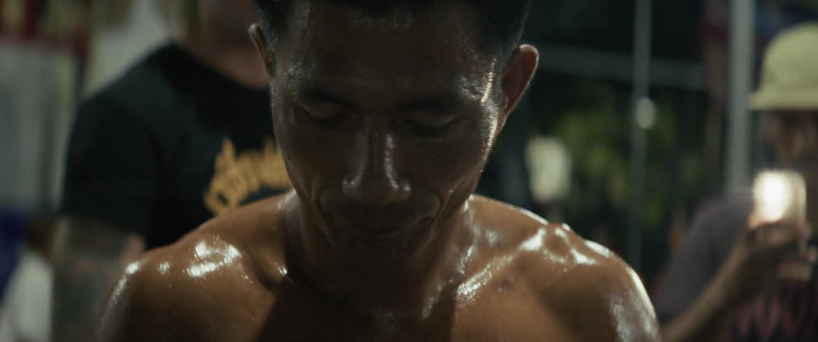 Intense slow-motion close-up of a sweaty, muscular man's face and shoulders at night