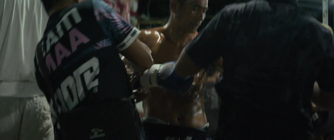 Trainers wrap a fighter's hands and rub oil on his body in slow motion as he mentally prepares for a match