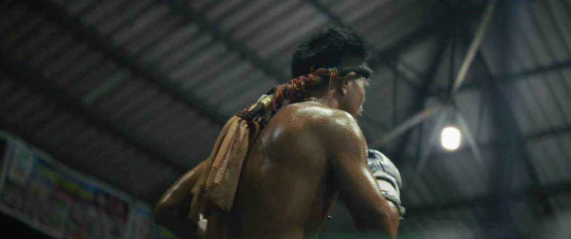 A dramatic, slow-motion close-up of a Muay Thai fighter performing a ritual dance in the ring before a match