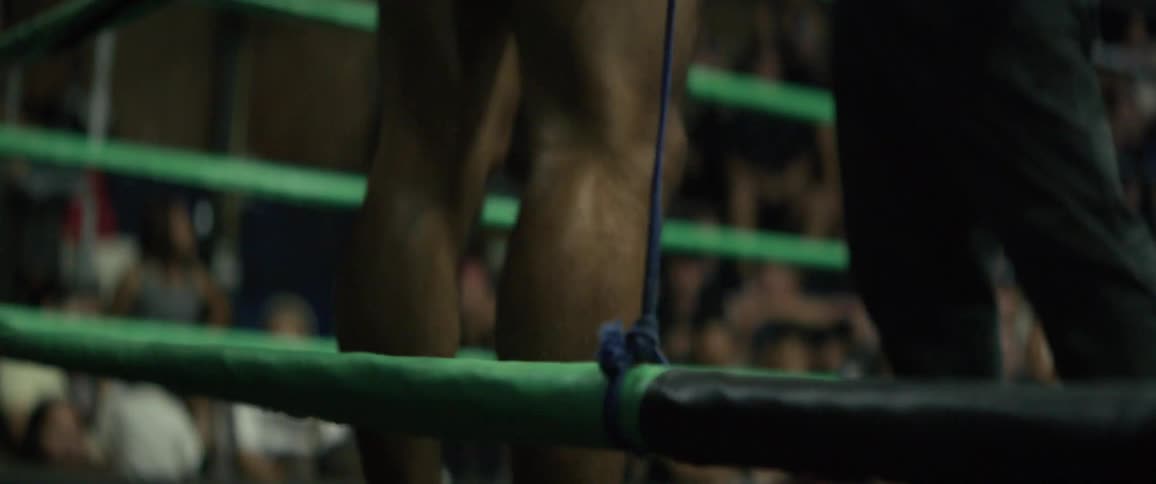 An intense, low-angle, slow-motion tilt up from the feet of a Muay Thai fighter waiting in the ring