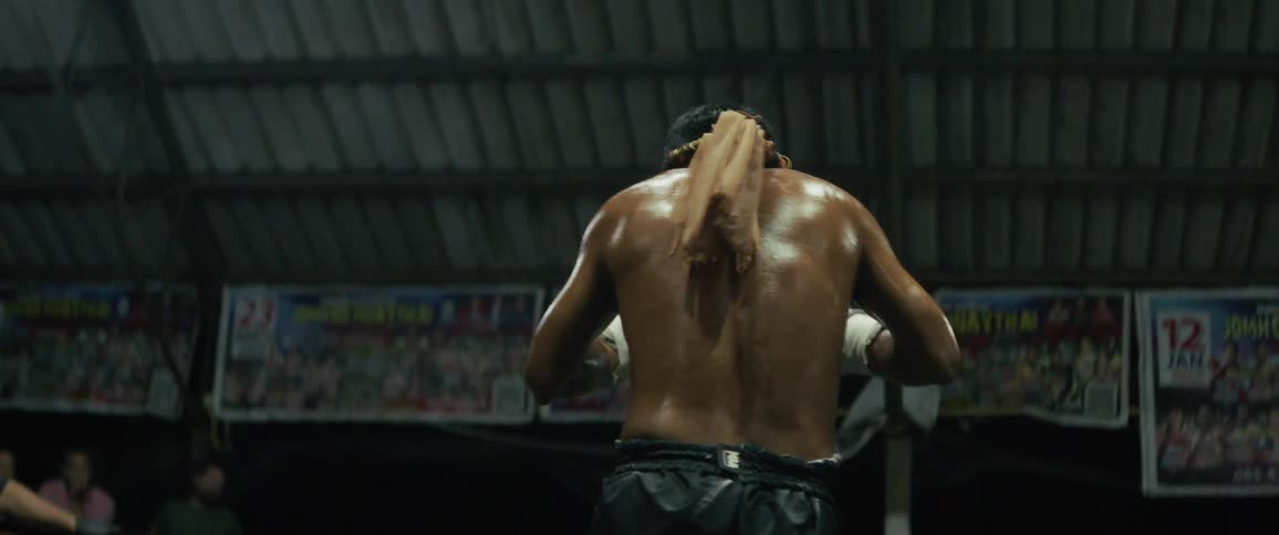 A focused Muay Thai fighter performs the traditional Wai Khru ritual in the ring before his match as the crowd watches