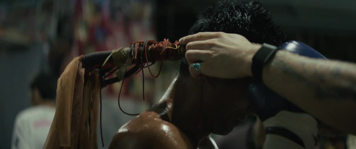 A Muay Thai fighter participates in a traditional pre-fight blessing ritual, receiving a Mongkol on his head in slow motion
