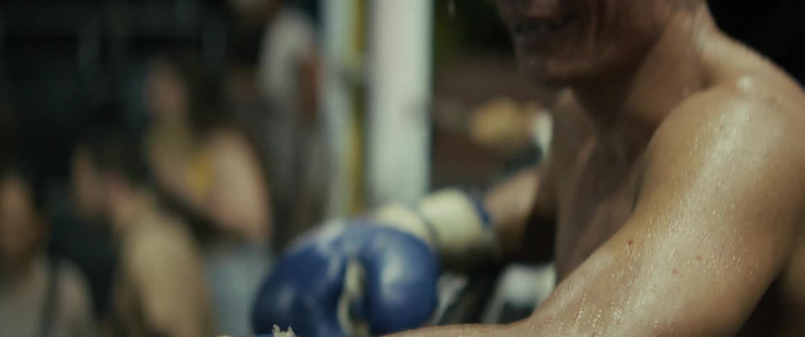 An intimate slow-motion close-up of a sweaty male fighter smiling and showing relief after an intense match
