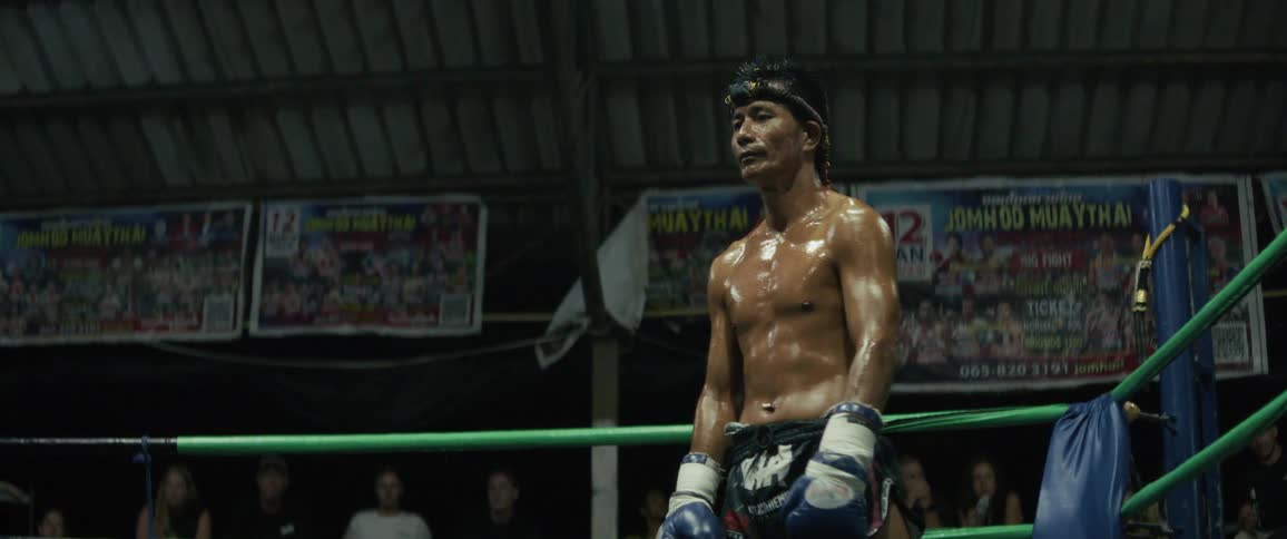 A determined Muay Thai boxer performs the traditional Wai Khru Ram Muay pre-fight ritual in the boxing ring at night