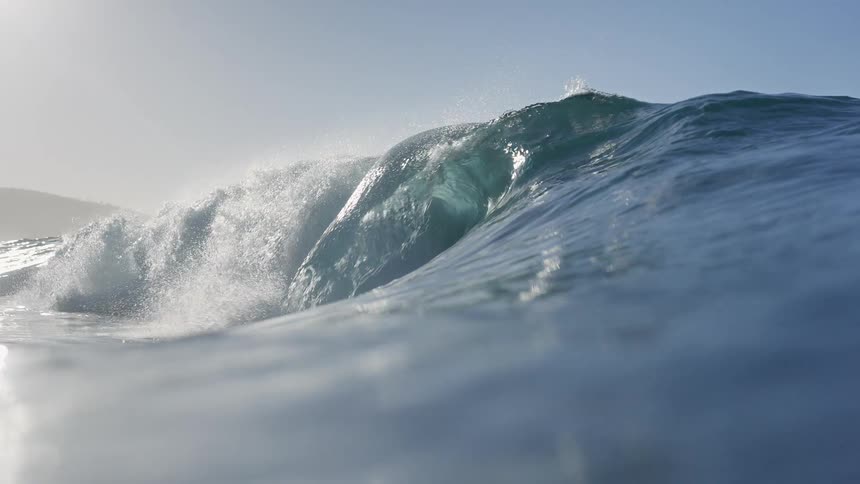 Mesmerizing slow-motion, water-level view of a perfect ocean wave cresting before the camera submerges