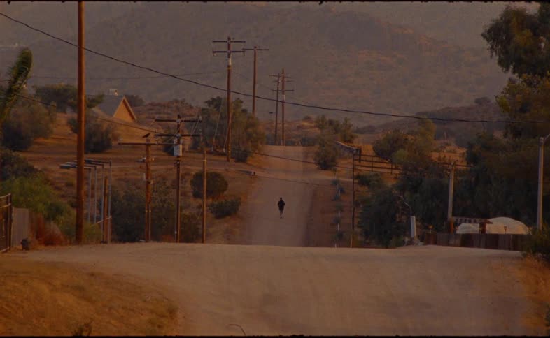 A solitary runner jogs up a dusty country road into the warm glow of sunset