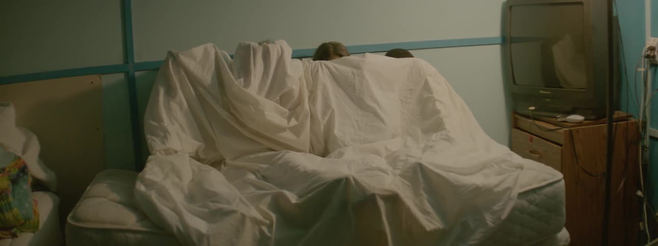 Four people hide behind a white sheet