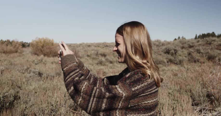 A woman takes a picture in a rural area on a sunny day