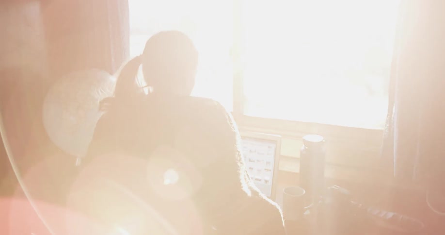 A woman sits down at a desk to work on a laptop