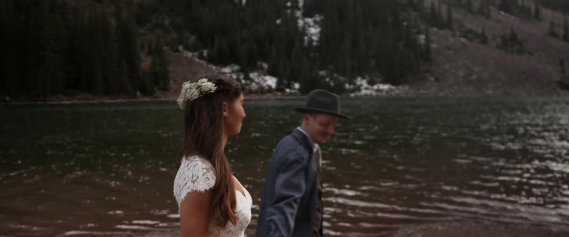 A man and woman hold hands walking by a lake