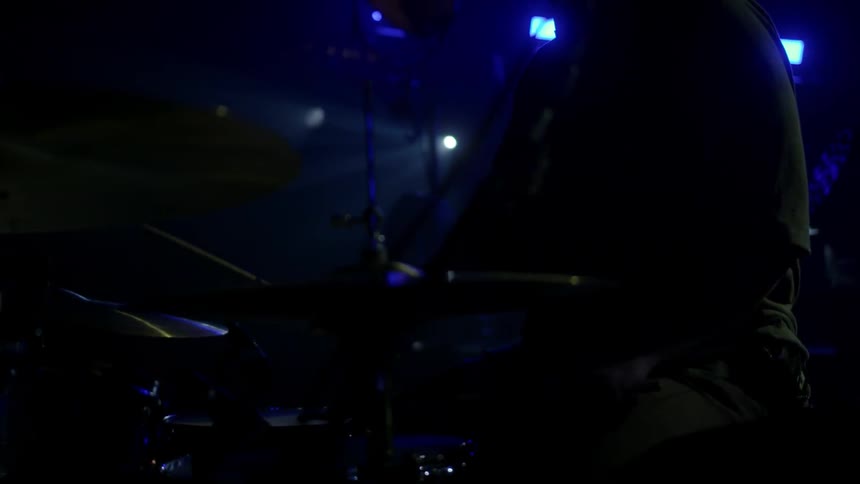 A man is playing drums in the dark