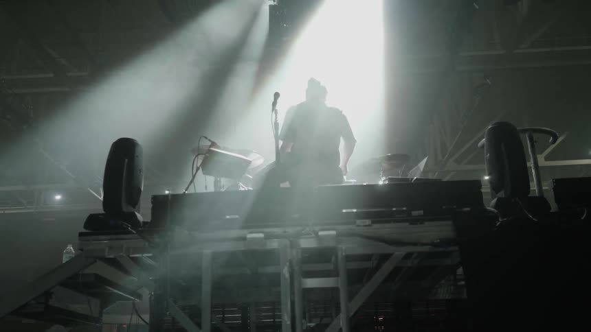 Spotlights shine on a drummer playing on stage