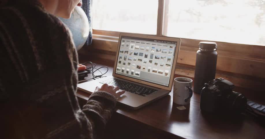 A woman scrolls through pictures on her laptop