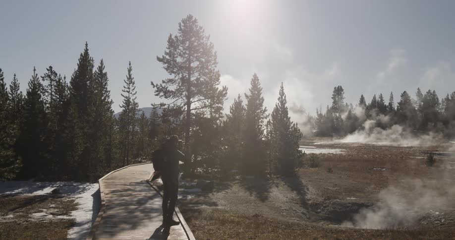 A man takes pictures of the steam rising from hot springs