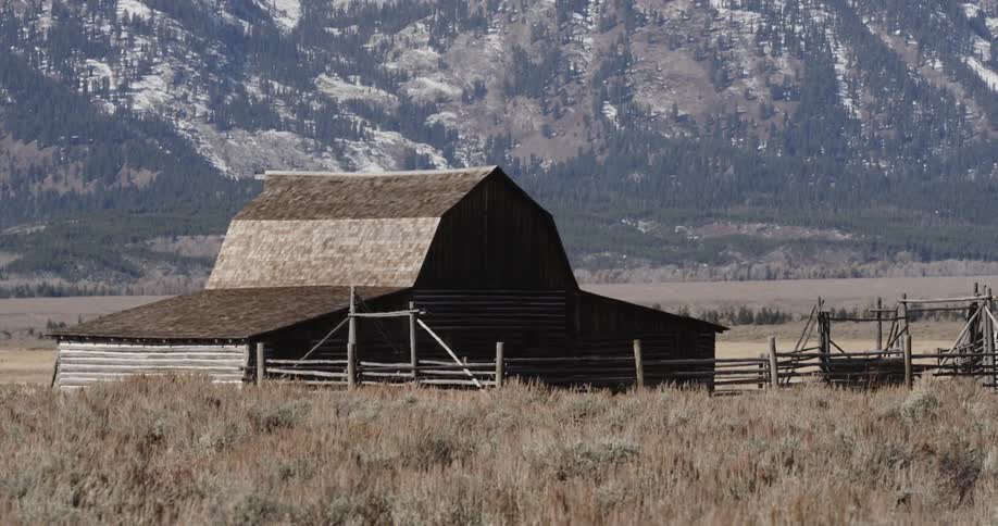 A large farm house has a wooden fence in front