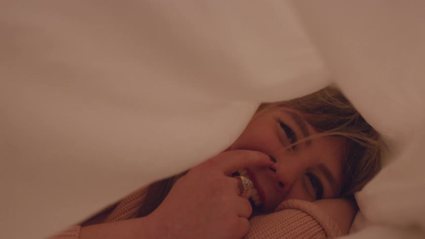 A woman laughs as she lies under a billowing sheet