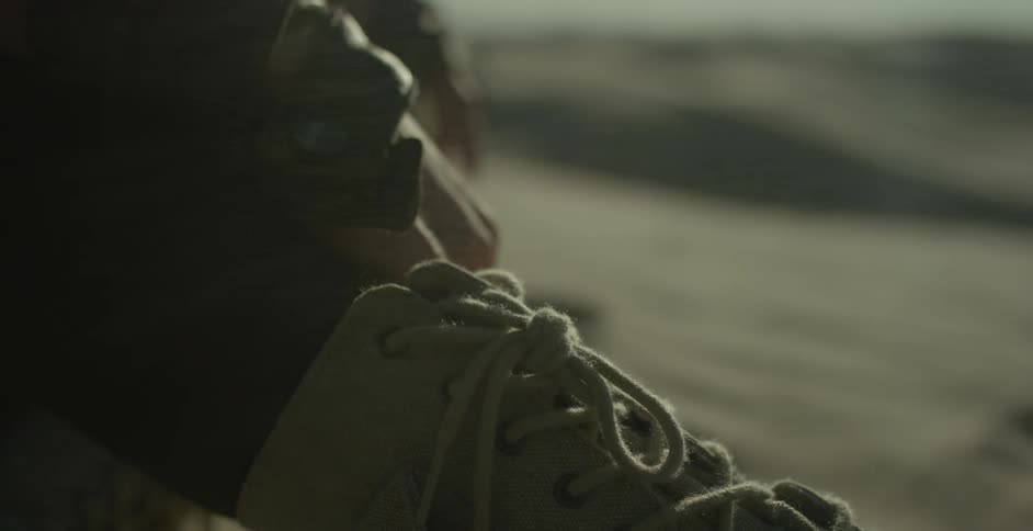 Sand blows across a sitting person's foot