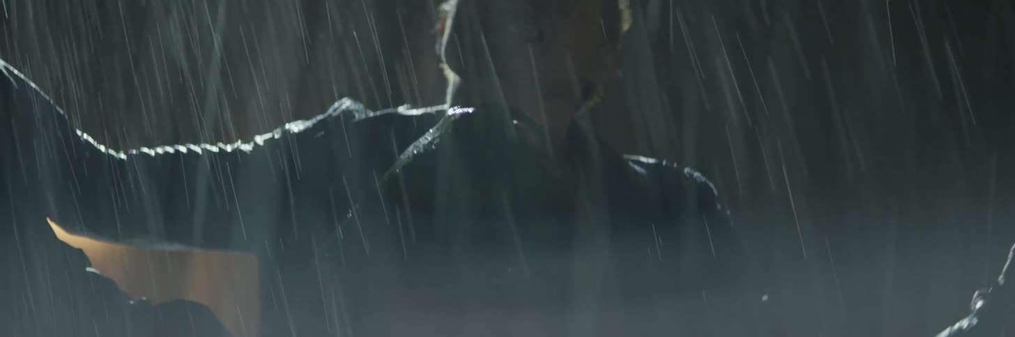 A man is walking through the field in the heavy rain