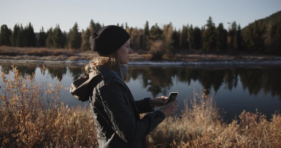 A woman in a beanie takes a picture with her phone
