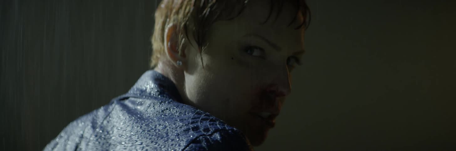 A woman with a bloody nose turns around in the rain