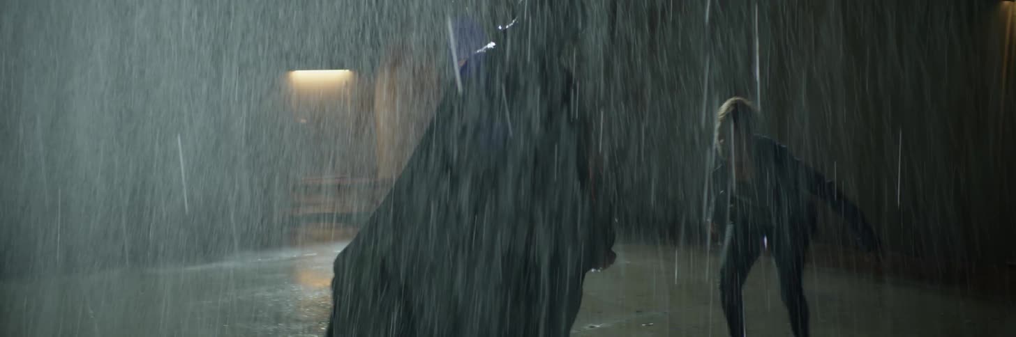 A woman is attacking a large man outside in the rain