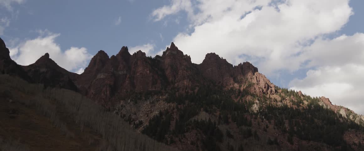 Clouds hover over rocky mountain peaks