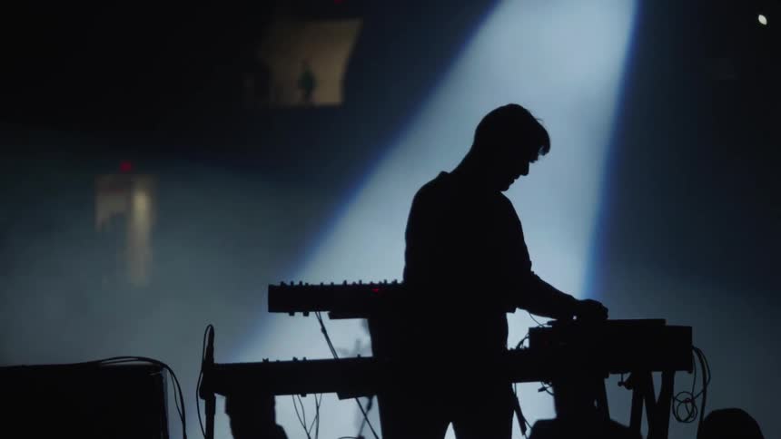 Silhouette of a man playing a keyboard on stage