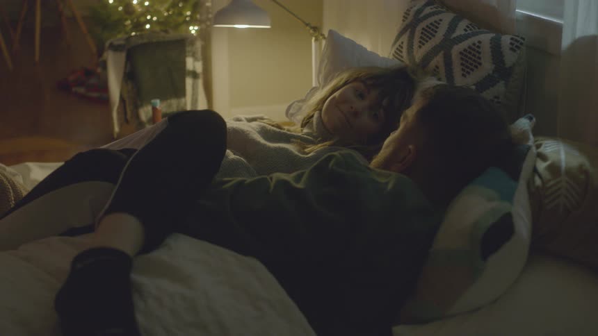 A man and woman cuddle while talking in bed