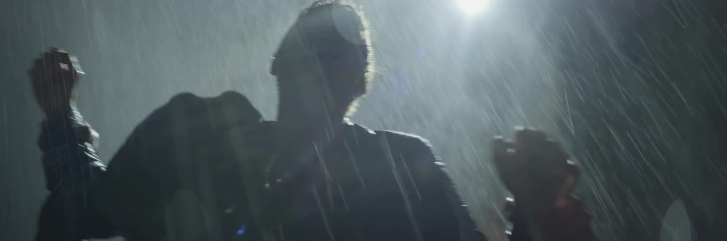 Two people fight each other in the rain at night