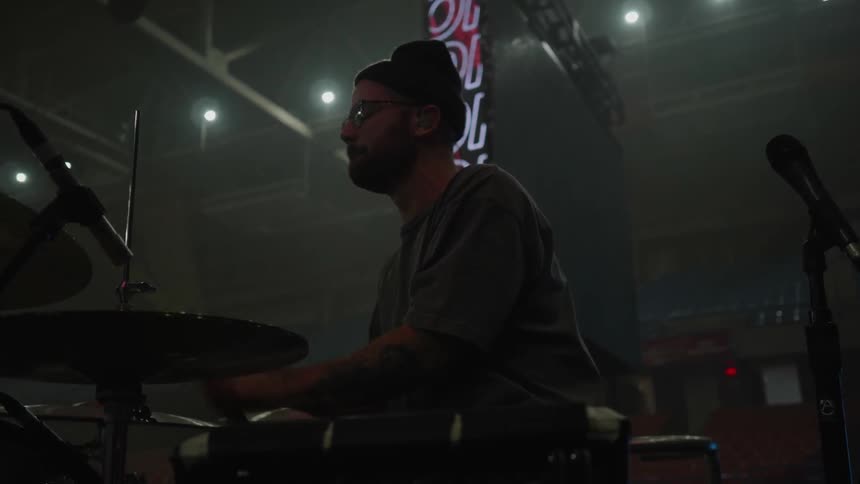 A drummer plays on stage at a concert venue