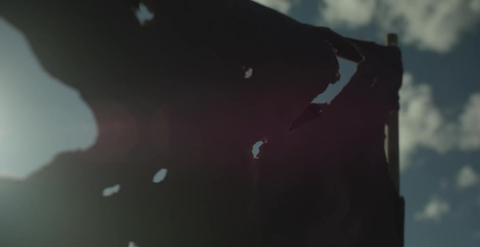 A tattered black cloth waves in a breeze