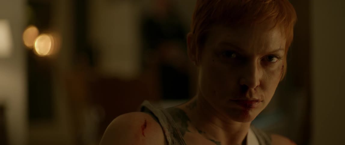A bruised, red-headed woman looks up