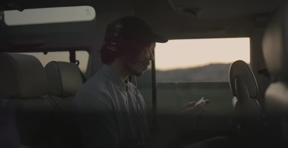 A man wears headphones while sitting in the backseat of a car