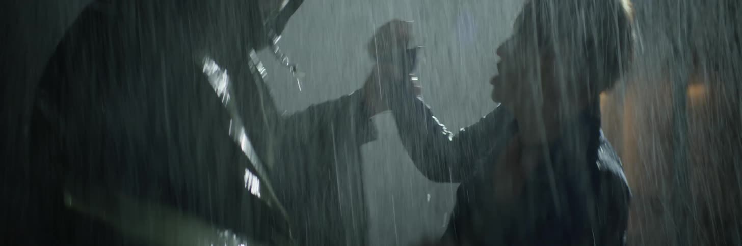 Two people fight each other in the rain at night