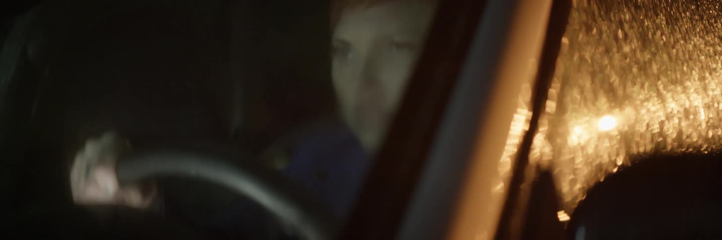 Angry looking woman sitting in a vehicle at night