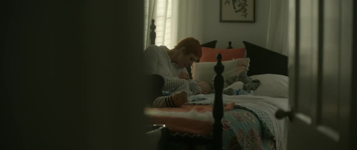 A mother lays with her baby in bed