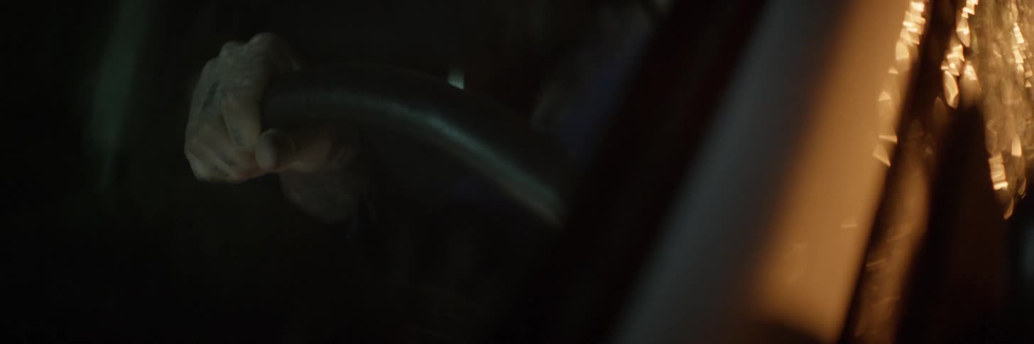 Hand gripping a steering wheel at night