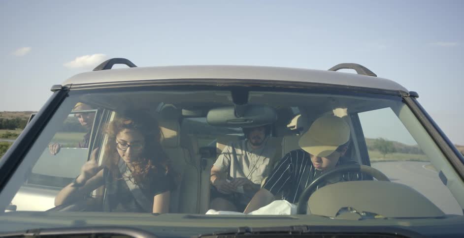 A group of people in a land rover talk and look around