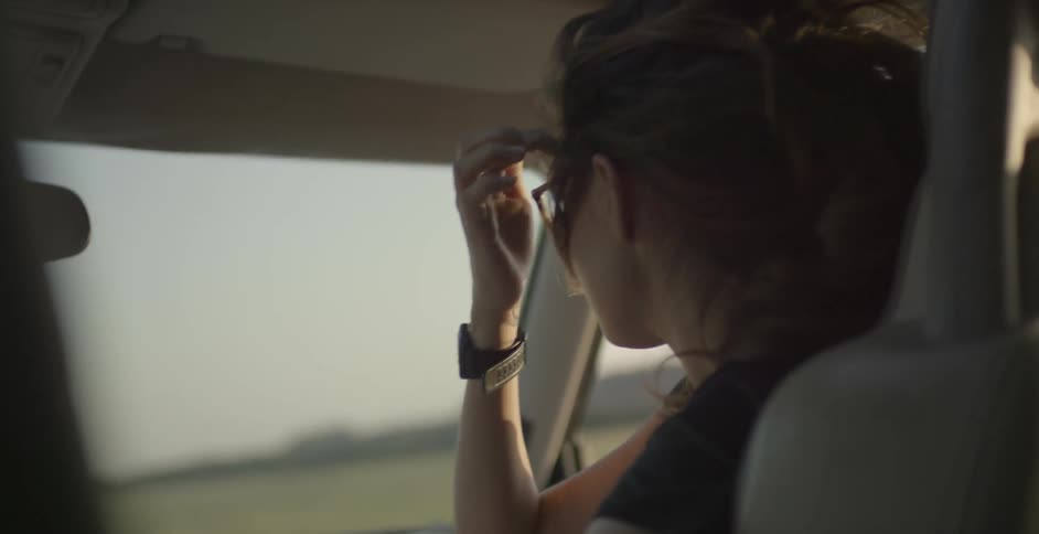 Woman riding in a vehicle takes and points her finger