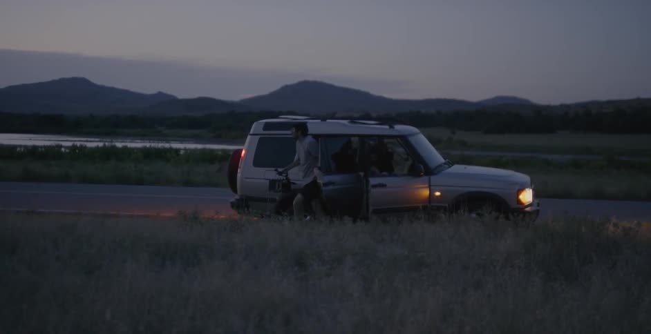A car pulling alongside the road and people getting out
