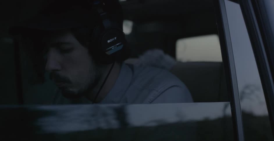 A man is wearing headphones riding in a car