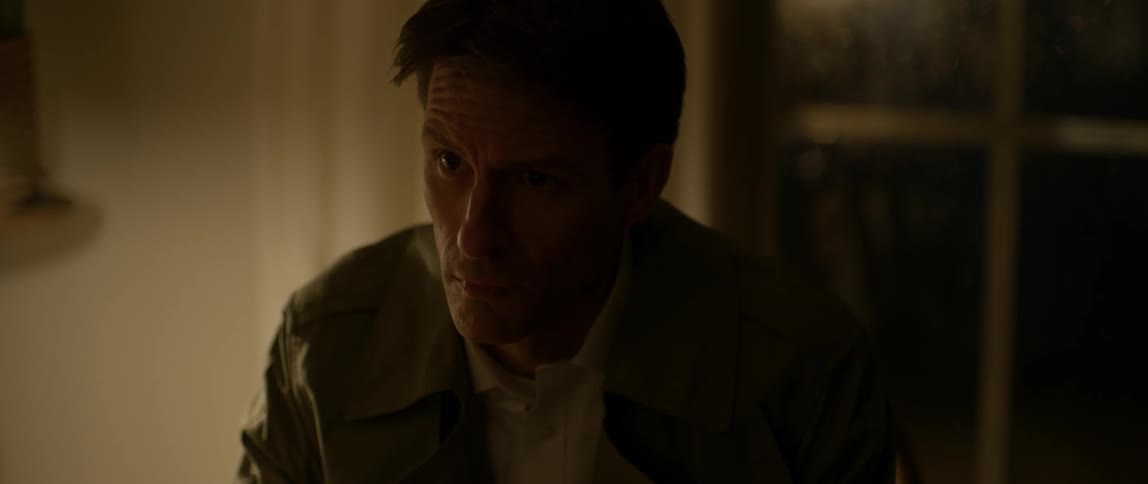 A man looks worried while sitting indoors at night