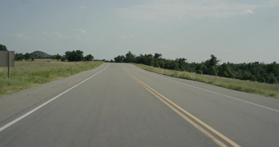 A country road stretches away as it is travelled on